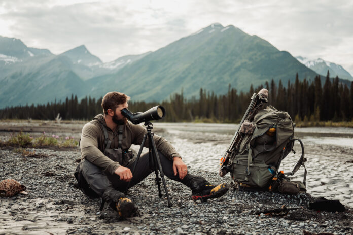The Next Level of Optics with Leica's Ryan Holm Man looks through Leica spotting scope in the mountains on a hunt